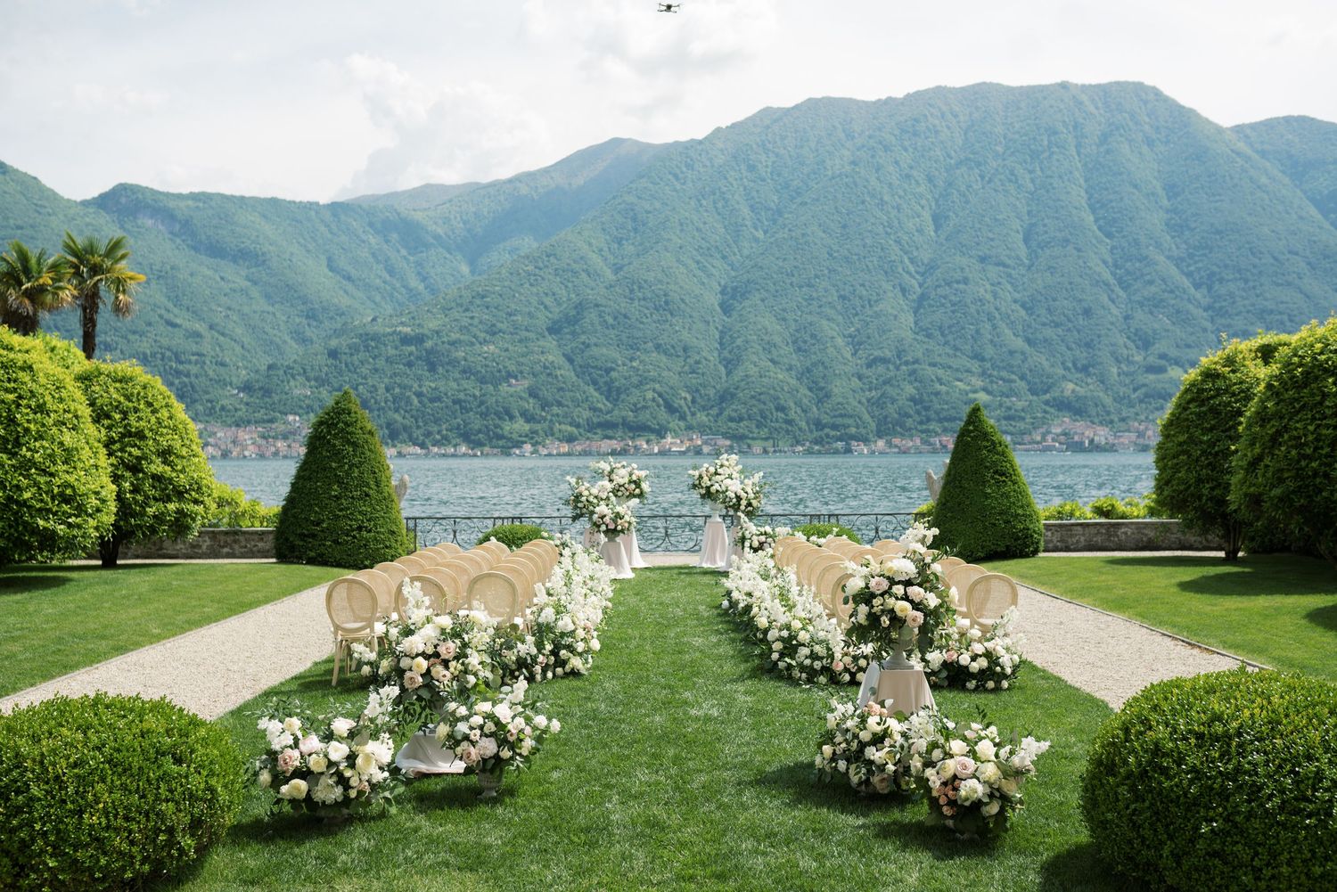 Panoramic view of Lake Como in Italy showcasing luxury villas, mountains, and lush gardens along the waterfront.