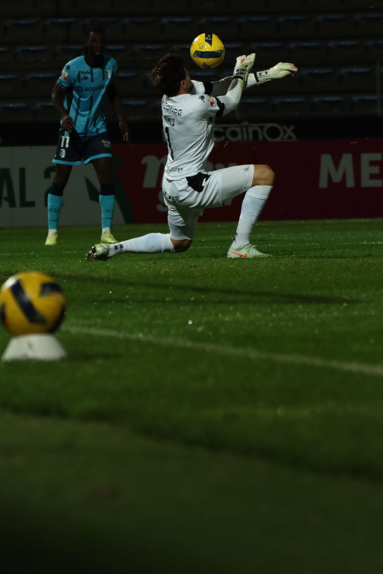 Soccer players compete for possession of the ball during an intense match between teams in yellow and blue uniforms.