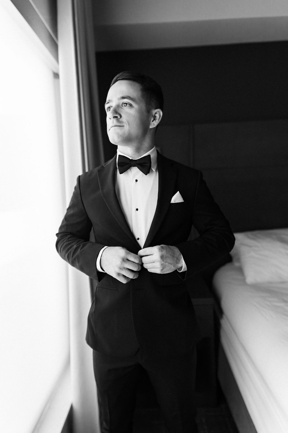 Black and white portraits of formal wedding attire preparation in window light.