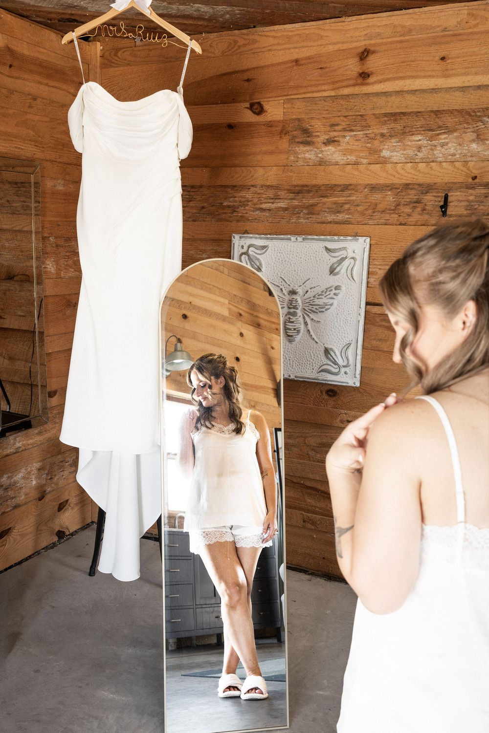 Series of shots showing a white wedding dress being prepared in a rustic wooden room.