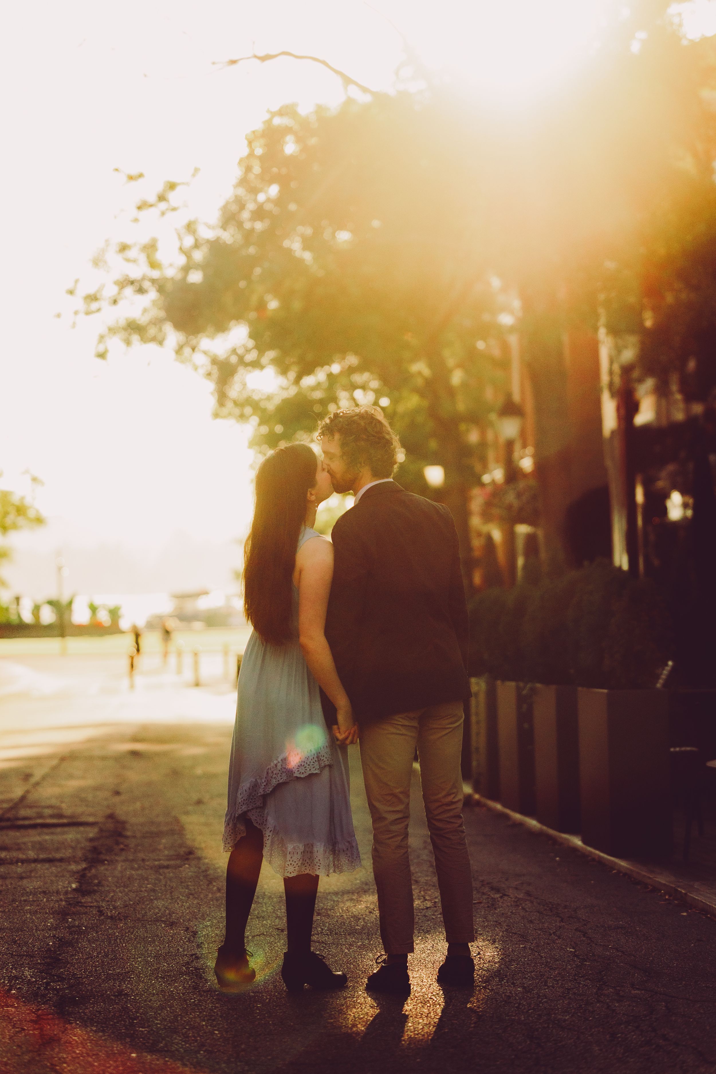 Silhouetted couple walking together on a path at sunset with golden sunlight filtering through trees.