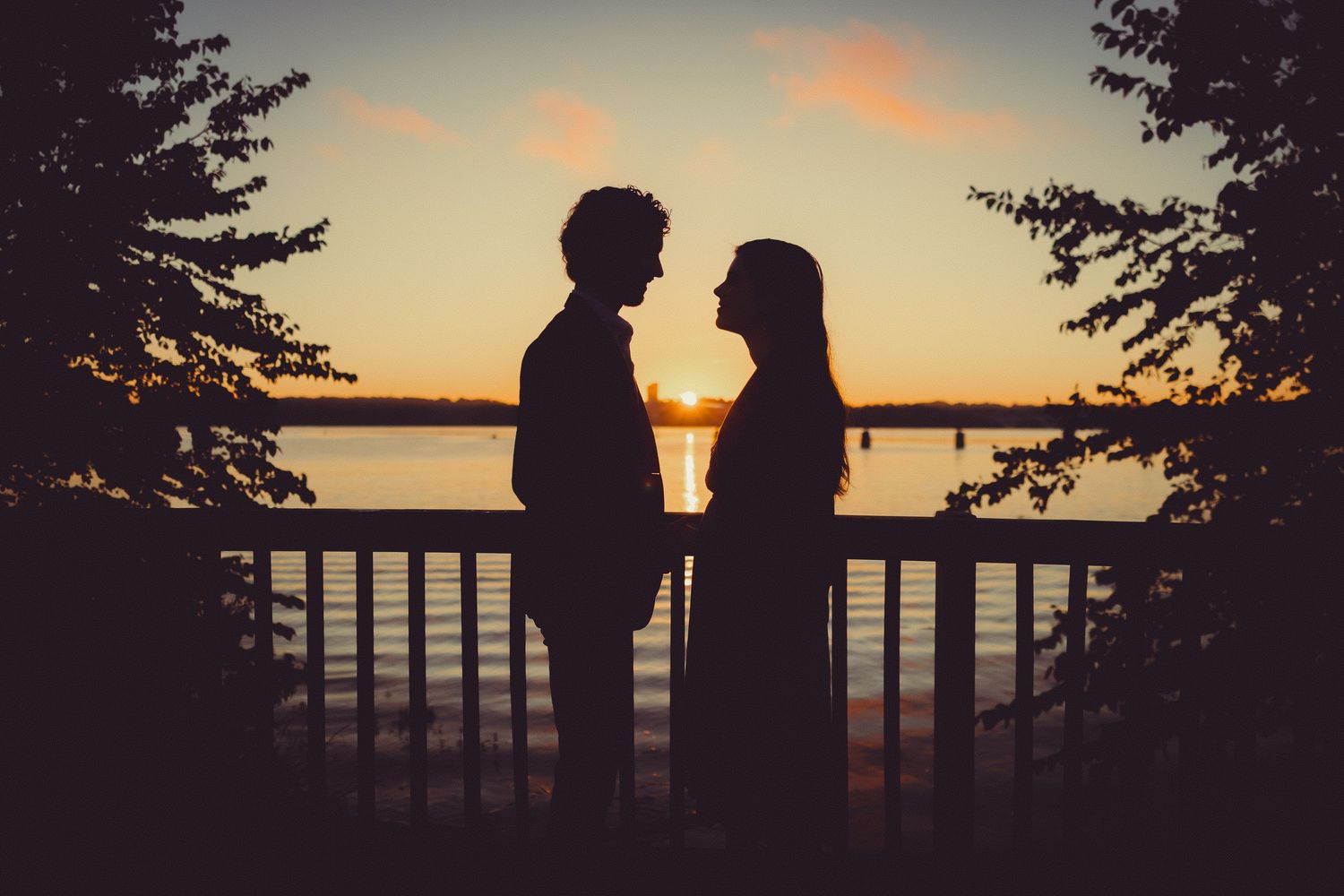 Couple walking hand-in-hand along the Alexandria Waterfront at sunrise with soft golden light
