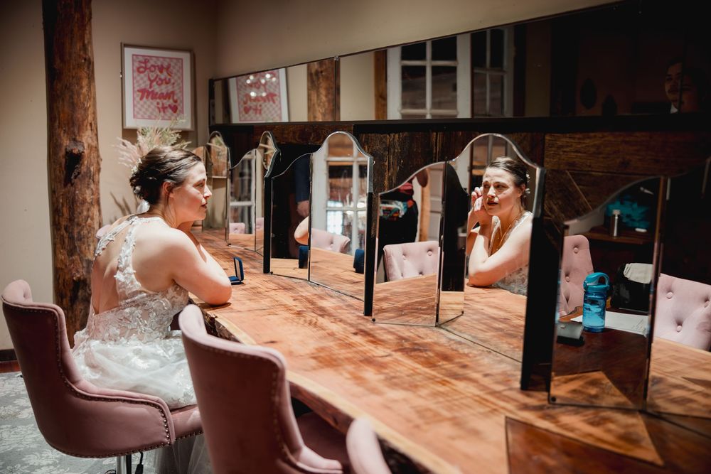 Wedding venue interior with brown leather chairs and wooden floors illuminated by natural sunlight through windows.