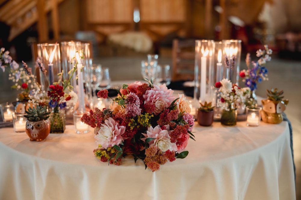 Elegant wedding reception tables decorated with romantic candlelight and colorful floral centerpieces in pink and red tones.
