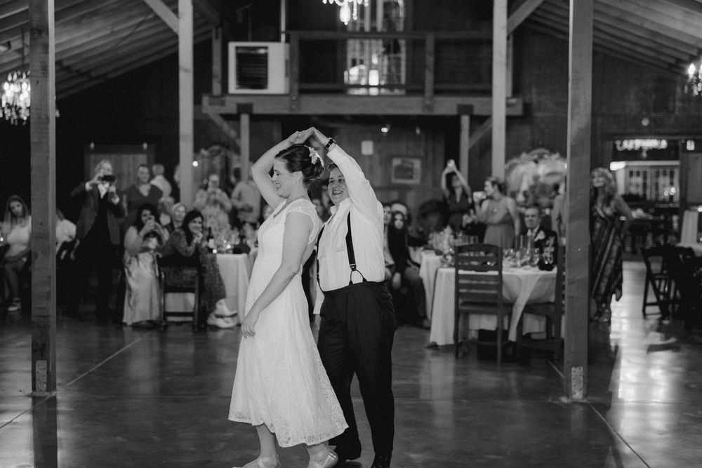 Couples dancing together on a spacious wooden dance floor at an indoor venue. lgbt