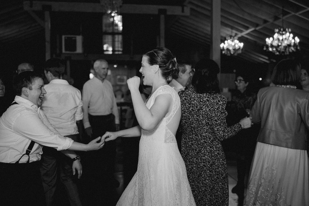 Black and white photo of couples dancing together at an evening wedding reception in a barn setting.