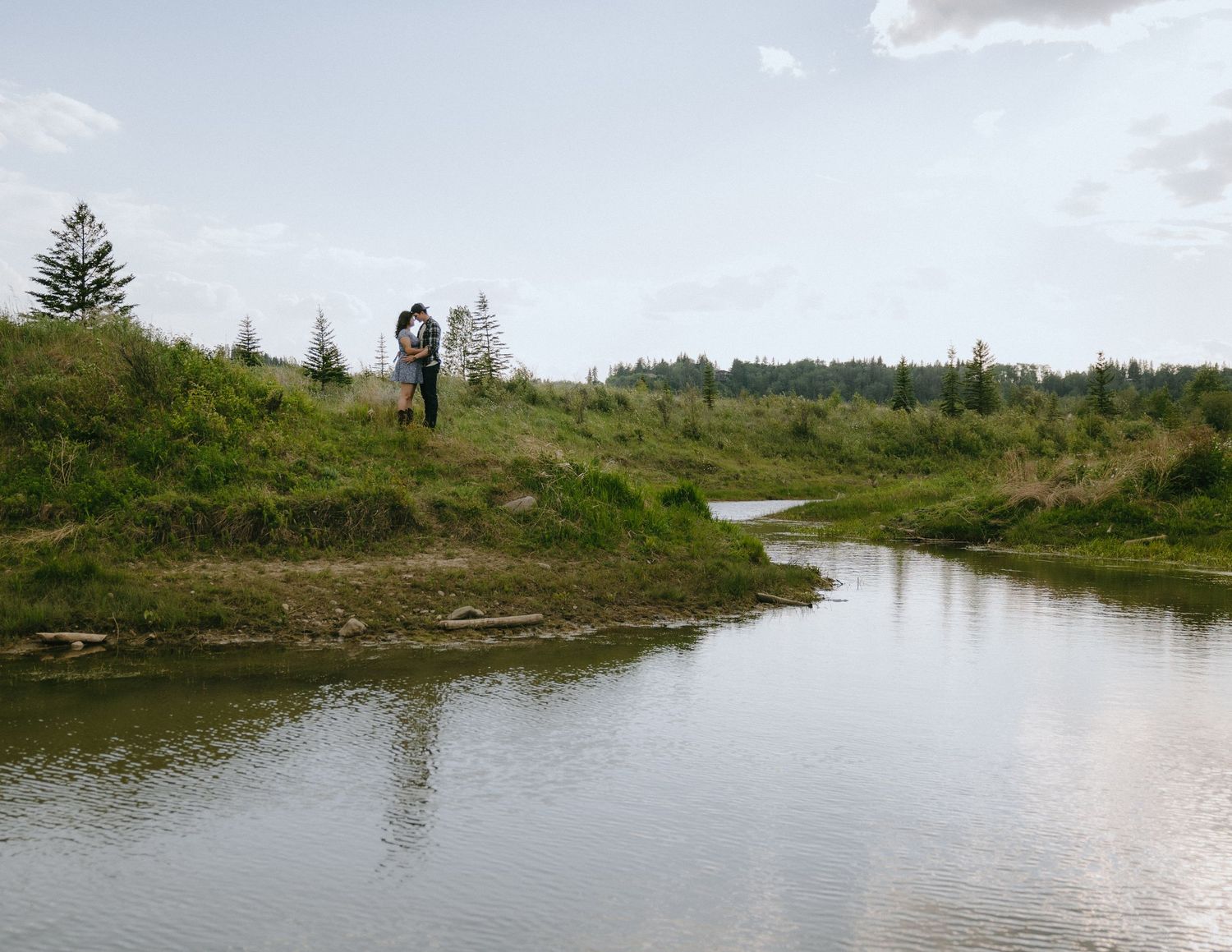 Scenic panoramic view of a winding river through green countryside with people walking along the grassy banks.