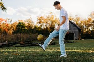 Soccer player dribbling a ball through an autumn field at sunset with warm golden lighting.