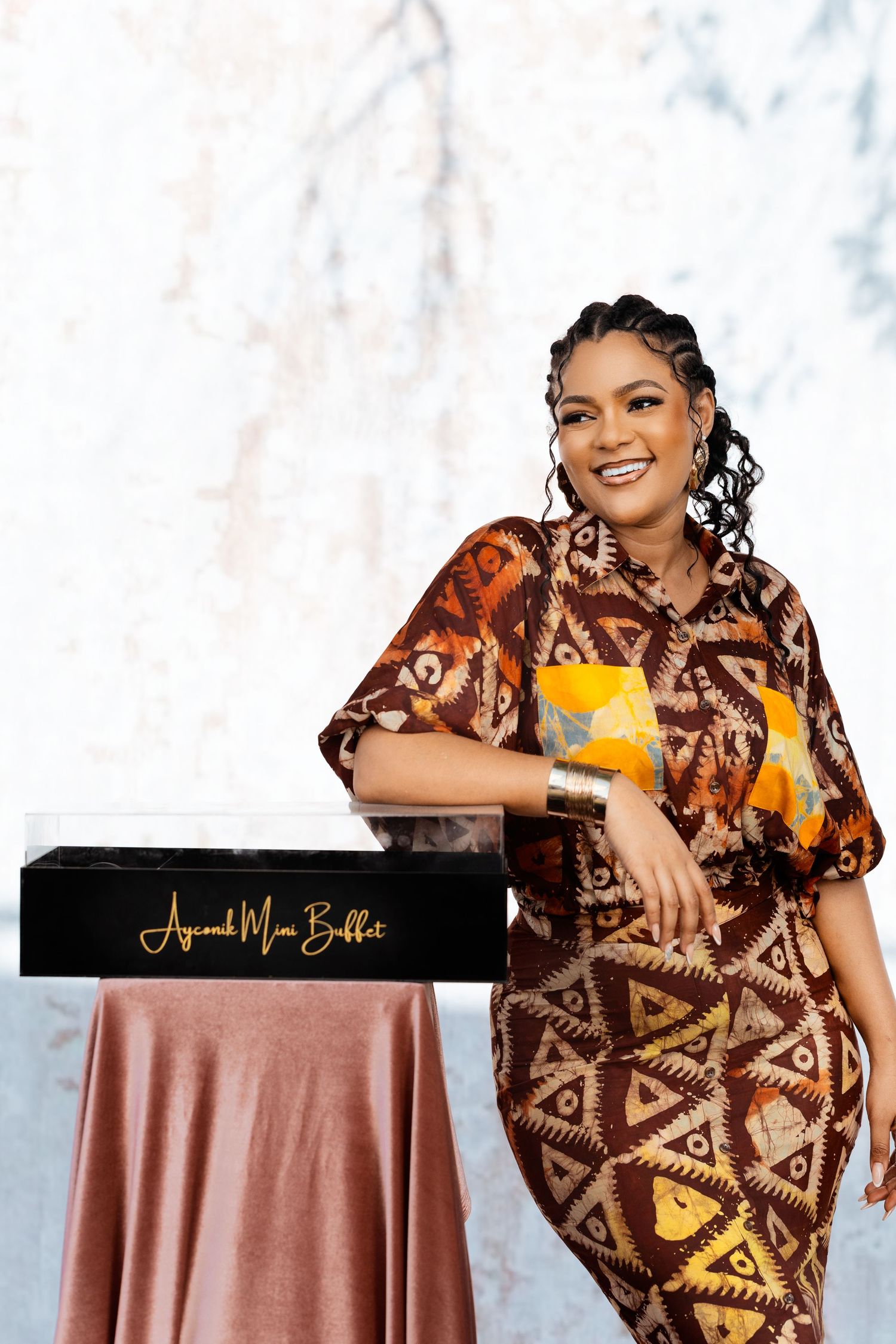Professional photo shoot with brown geometric patterned dress against white backdrop.