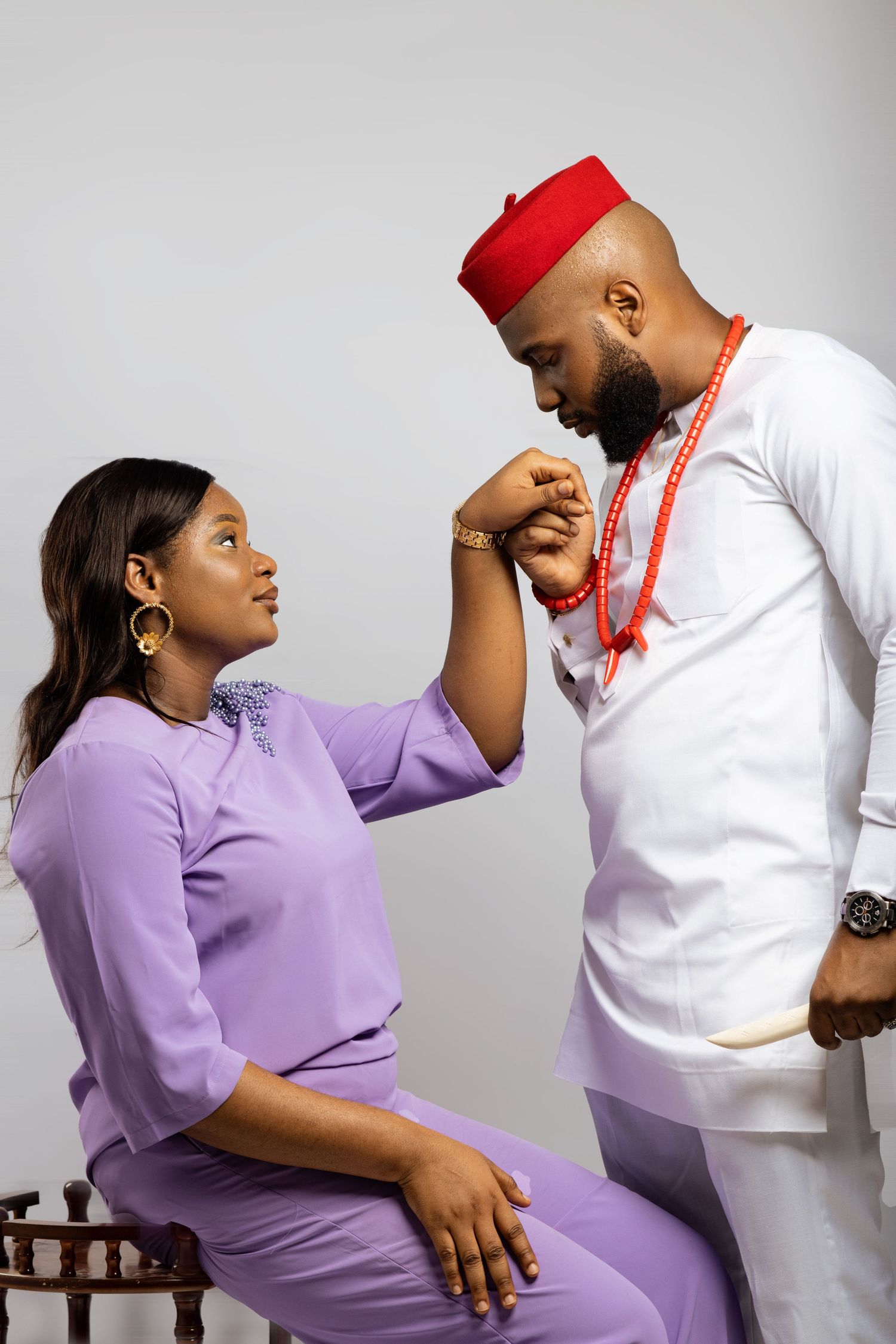 Playful couple's photoshoot with purple and white outfits against a light gray background.