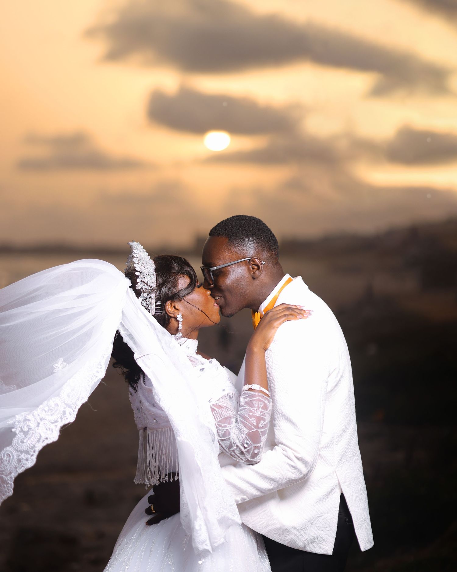 An intimate wedding moment captured during sunset with the couple in white attire.