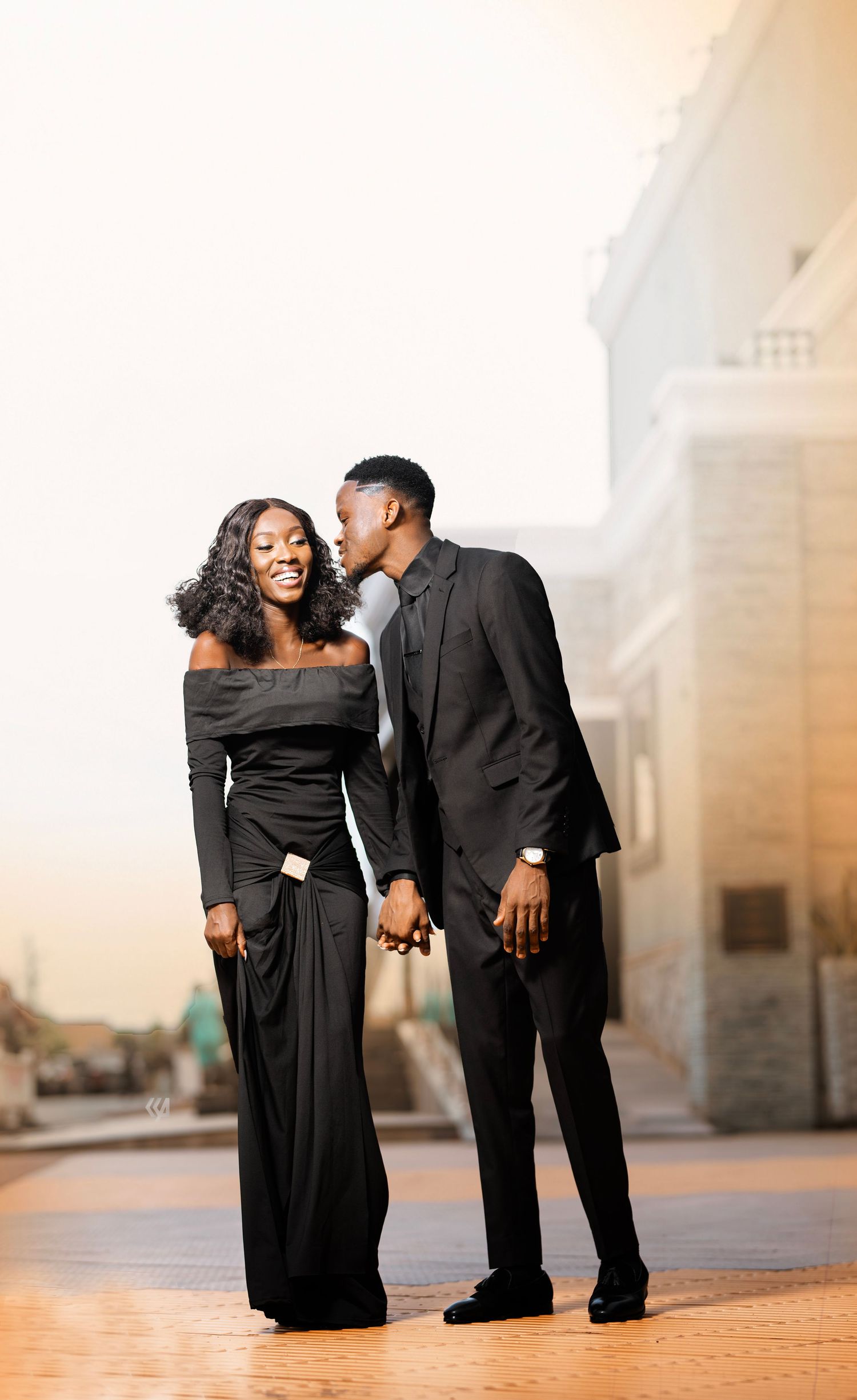 A couple shares joyful moments together outdoors in formal black attire.