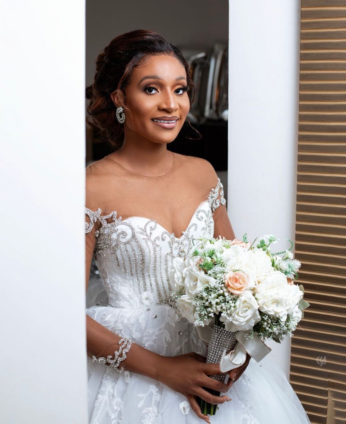 An elegant bridal portrait featuring a white lace dress and delicate bouquet of roses and baby's breath.