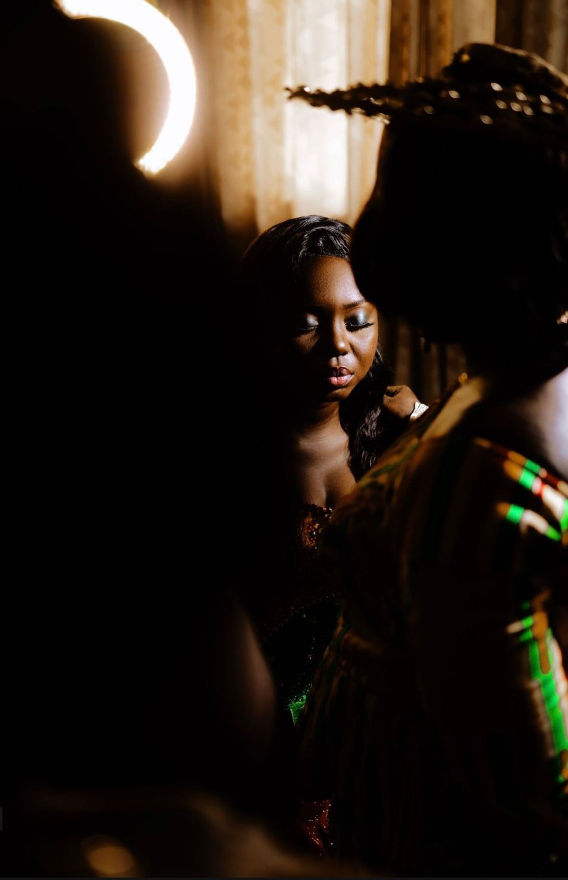 An artistic low-light portrait with dramatic shadows and green accent lighting.