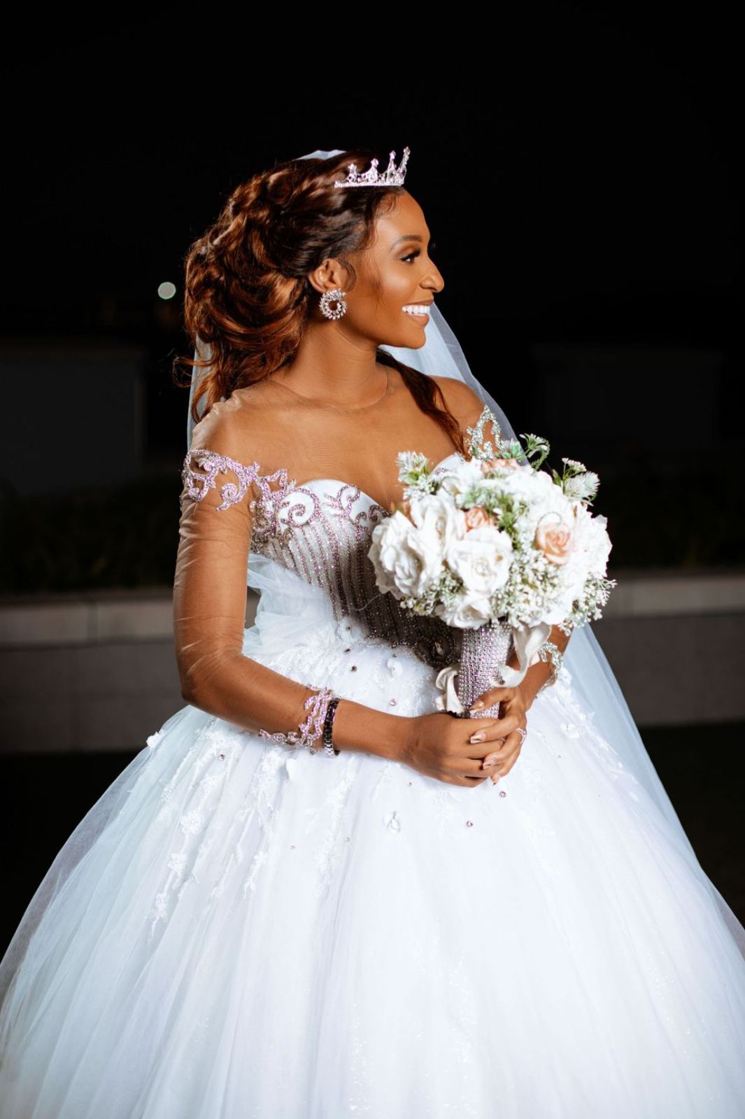 Close-up details of an elegant white wedding gown with lace details and floral bouquet.