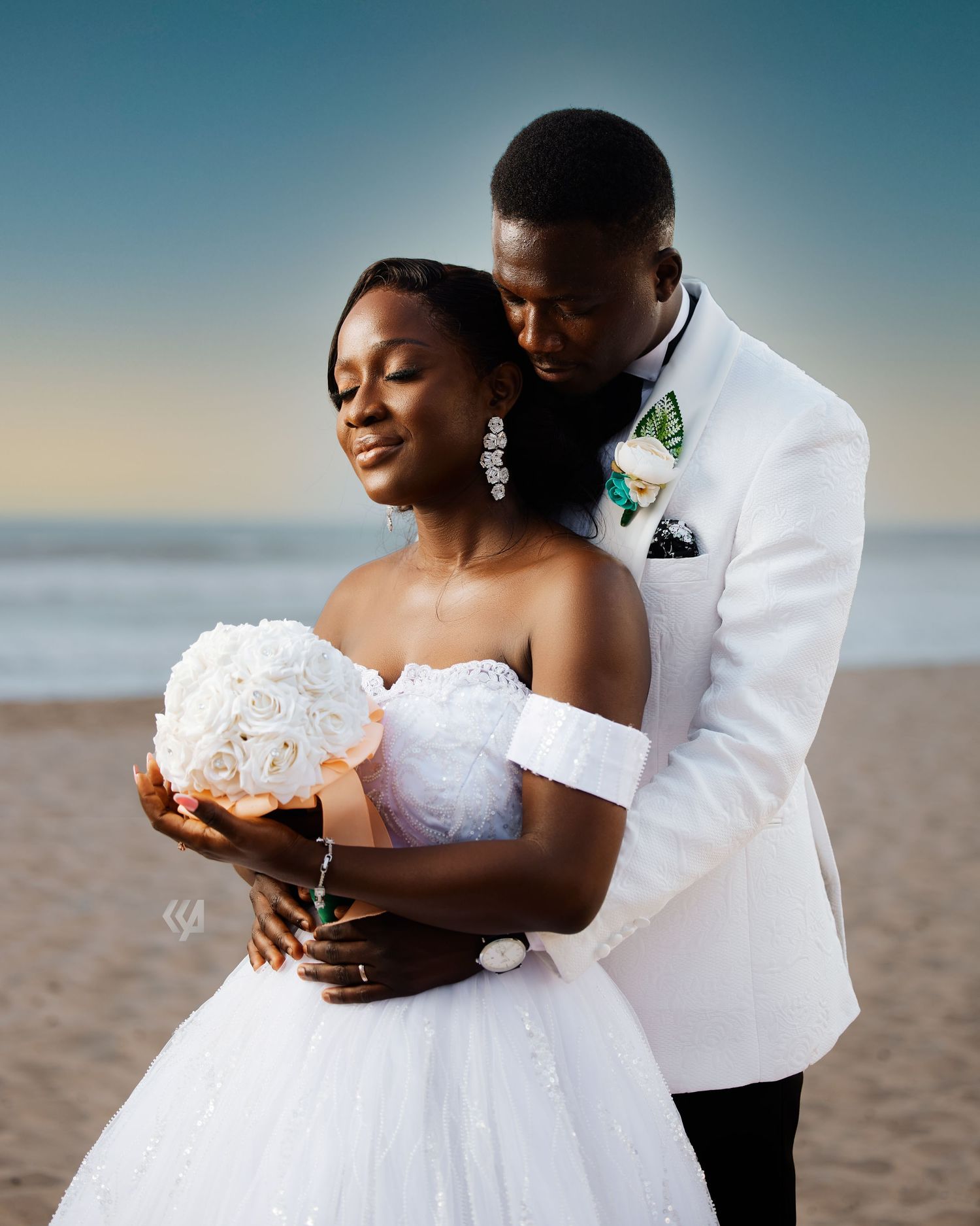 A tender moment between newlyweds on the beach with the ocean in the background.