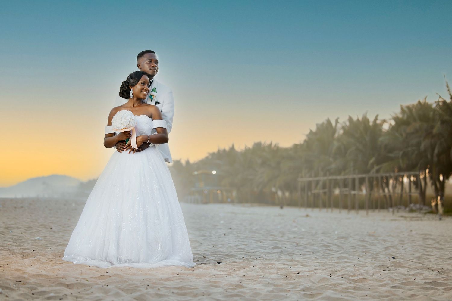Newlyweds share an intimate moment on a sandy beach at golden hour.