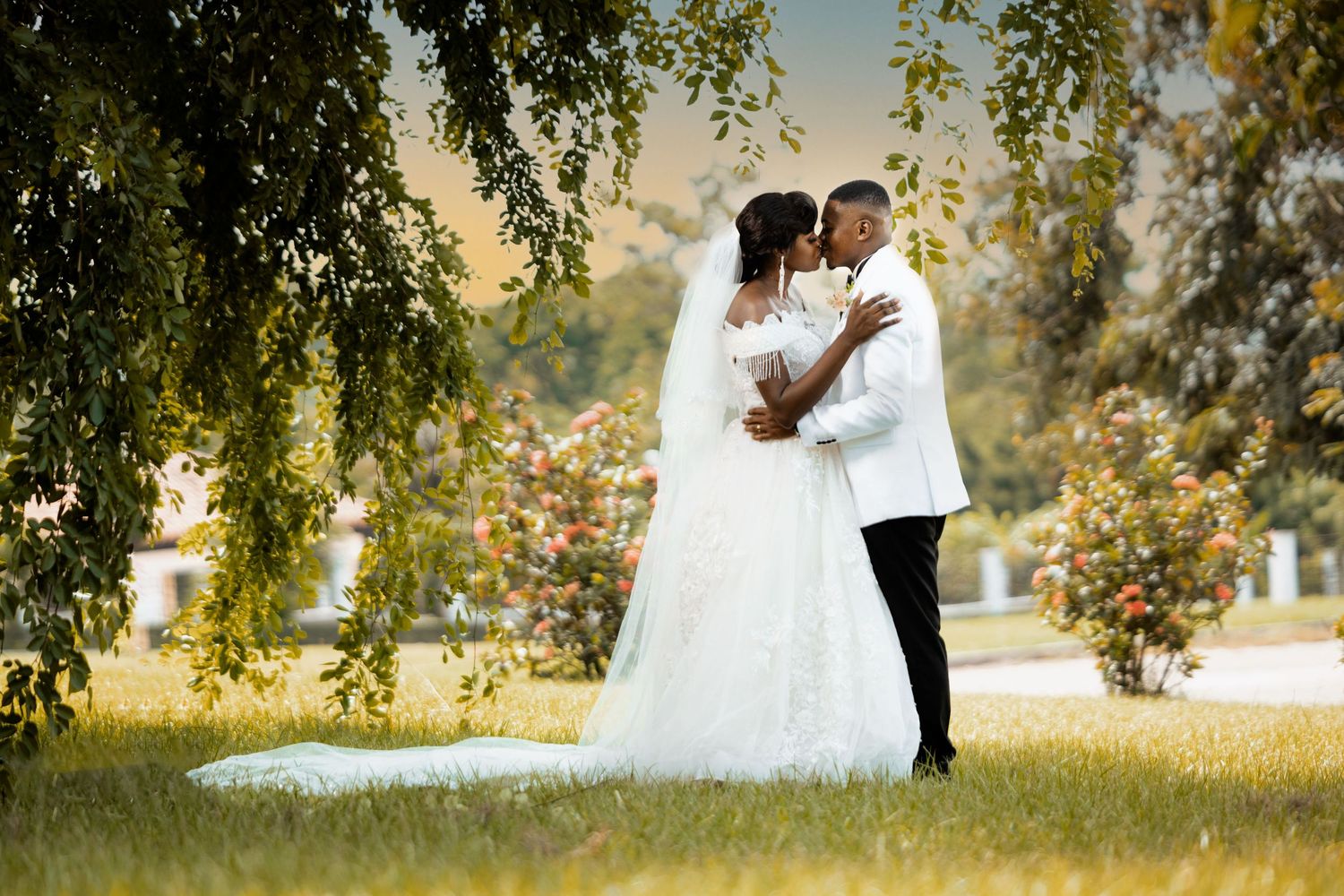 A romantic wedding portrait in a lush garden with willow trees.