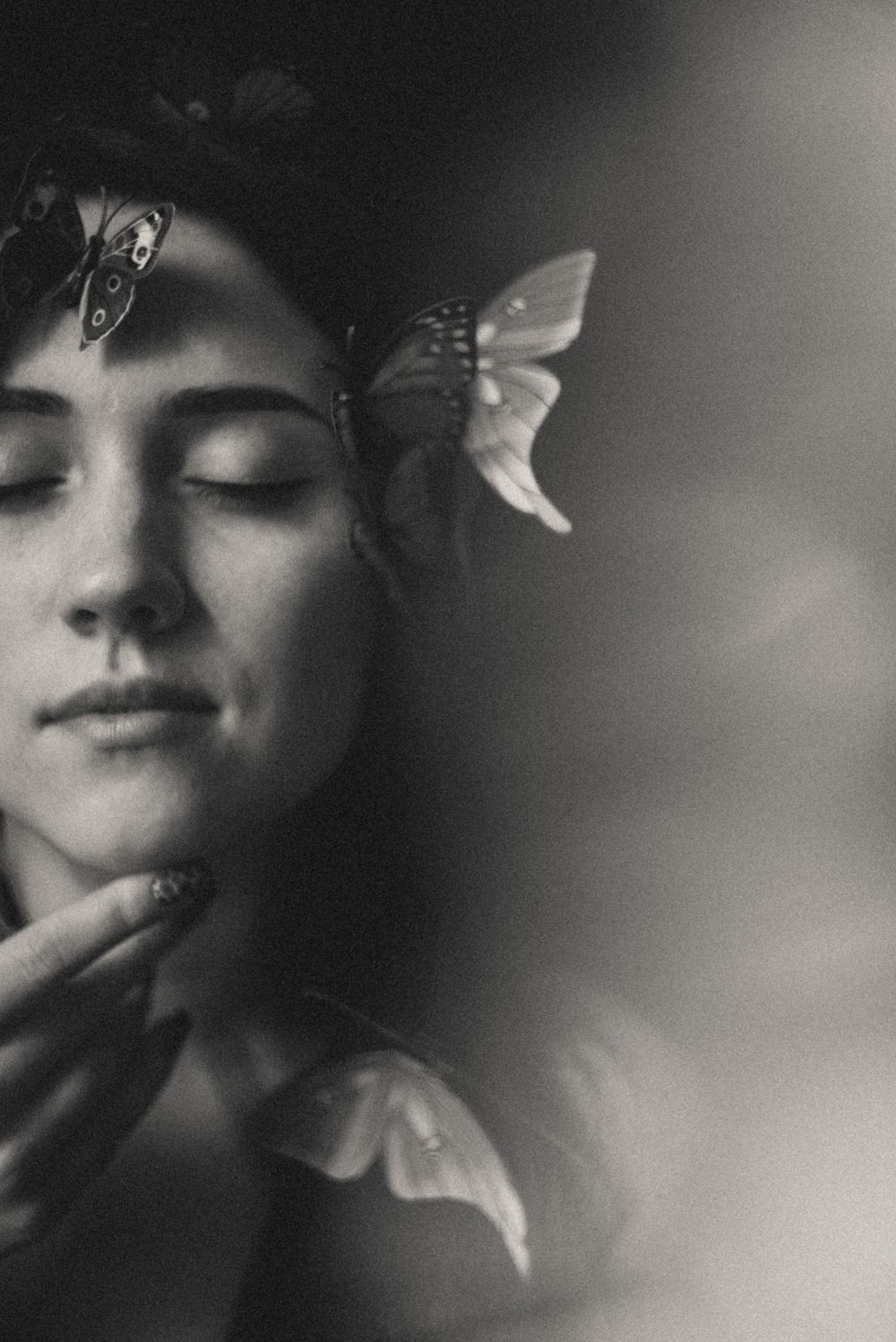 Artistic black and white portrait series showing ethereal close-up shots with delicate paper butterflies.