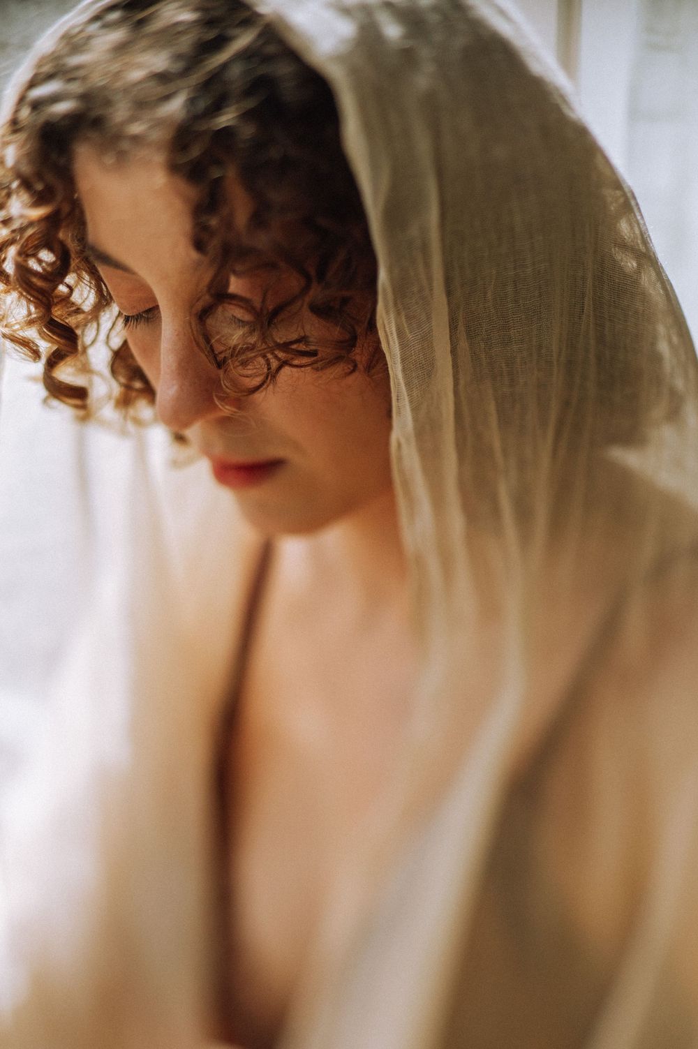 A soft, dreamy portrait sequence shows a figure with curly hair and red lipstick through sheer fabric in warm lighting.