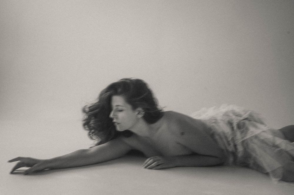 A series of black and white photographs showing a figure lying down in different graceful poses against a light background.