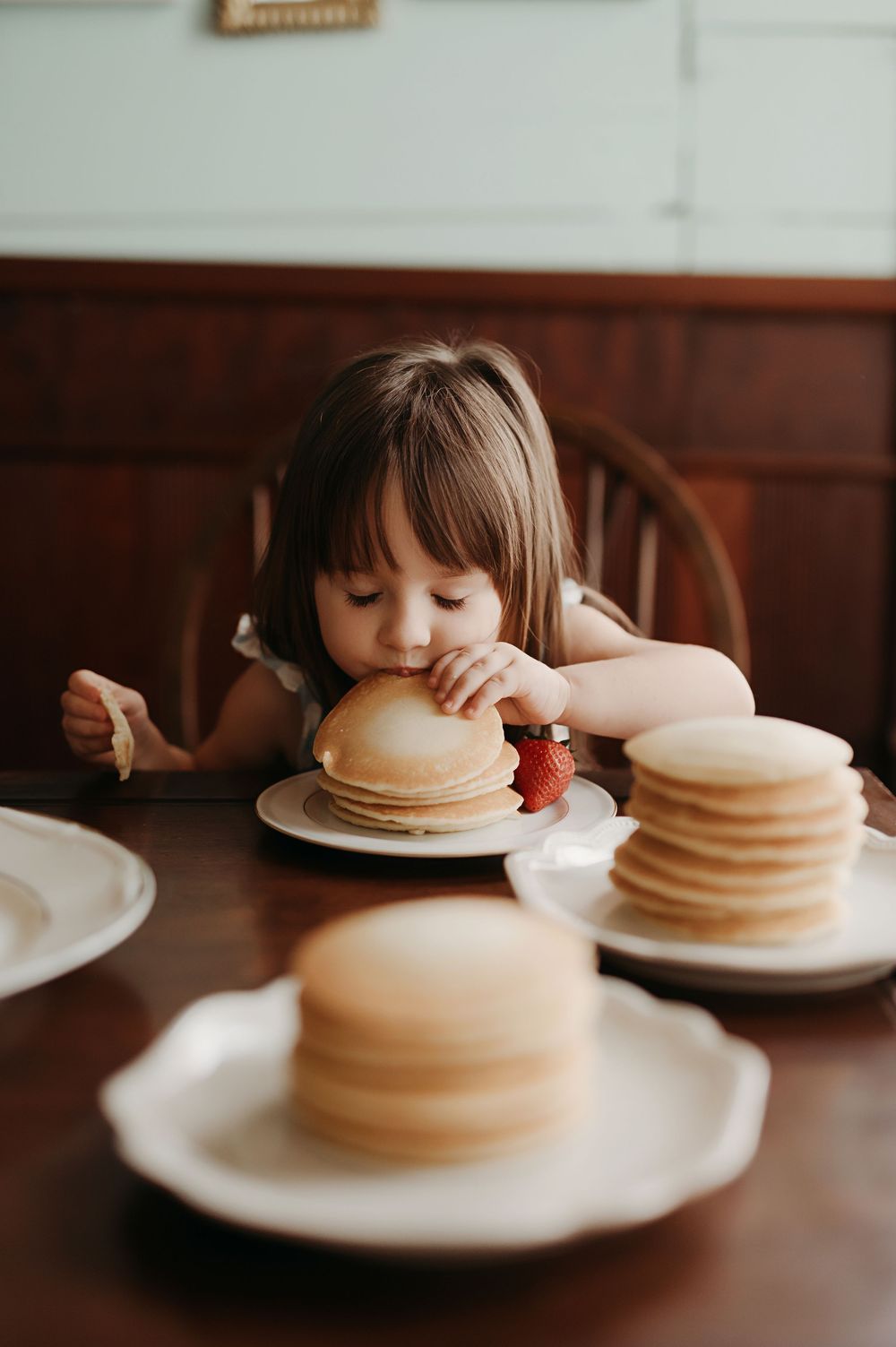 A stack of fluffy pancakes with butter and syrup on a white plate shown in a sequence of lifestyle photos.