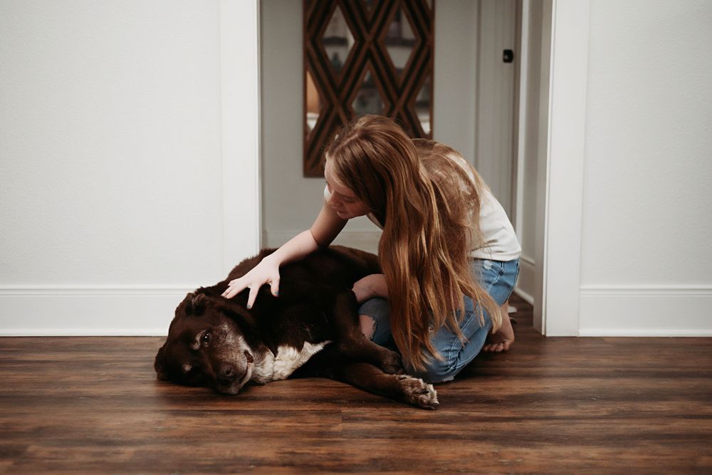 Person lying on hardwood floor with long hair spread out in artistic composition.