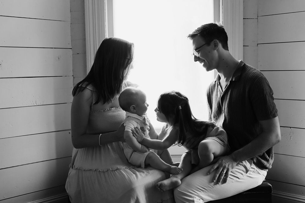 Black and white photo series showing tender moments between parents and babies in intimate domestic settings.