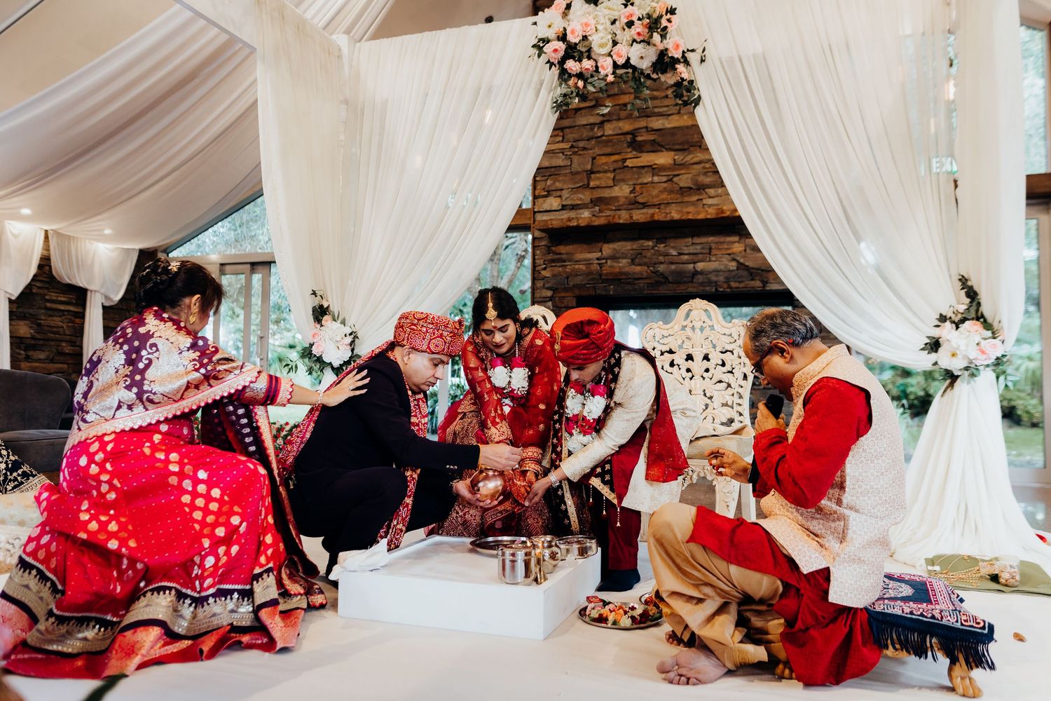 A beautiful outdoor wedding ceremony under a white gazebo surrounded by guests in a garden setting.