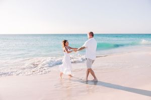 Couple walking and playing along pristine white sandy beach with turquoise waters.