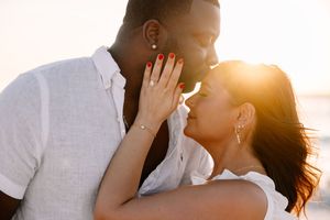 Romantic beach sunset moment with couple embracing against golden sunlight.