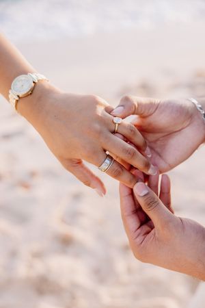 Close up of hands exchanging rings during beach proposal.