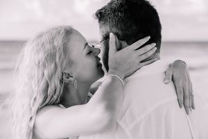 Black and white intimate portrait session capturing tender moments on the beach.