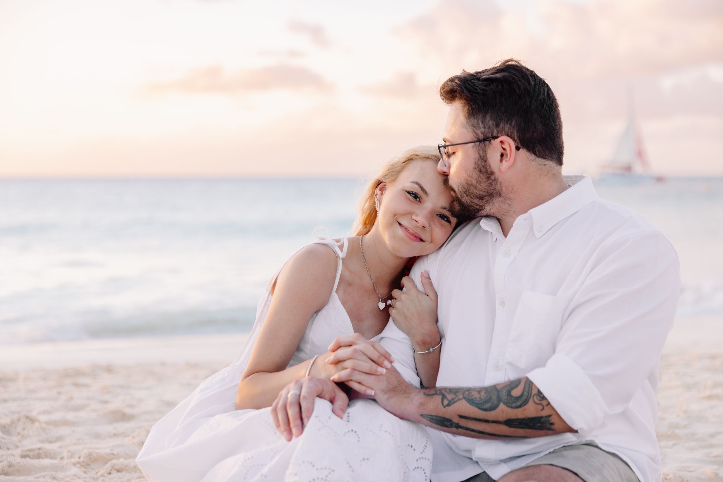 Romantic beach photography session during golden hour with soft pastel sky.