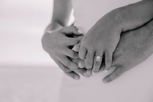 Black and white close-up of hands with engagement rings showing tender moments.