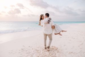 Joyful couple celebrating on white sandy beach with crystal blue waters.