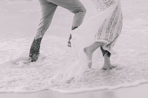 Feet kicking up sand during playful beach photoshoot at sunset.
