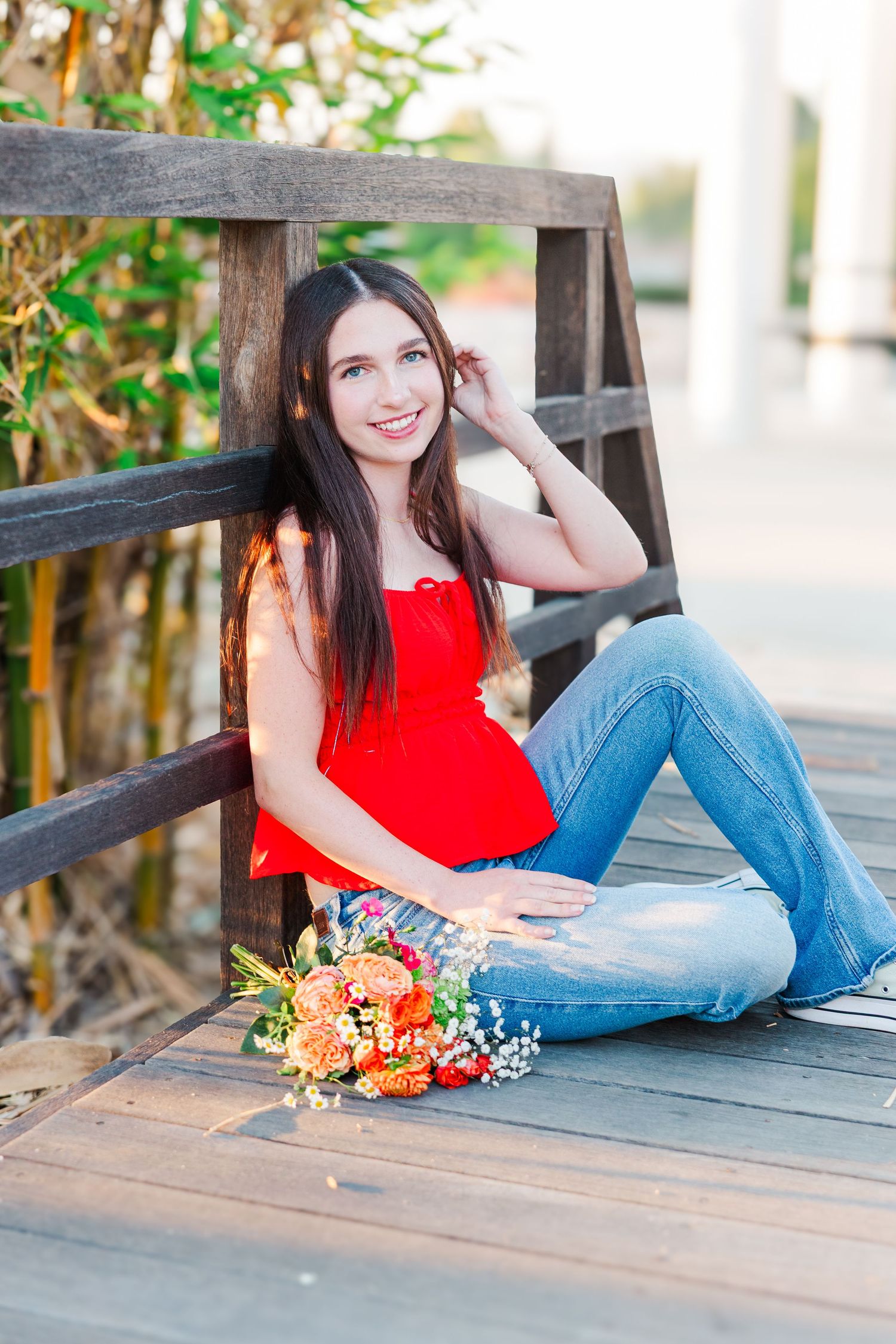 A series of outdoor portrait photos showing someone in a red sleeveless top and jeans relaxing on a wooden deck with flowers.