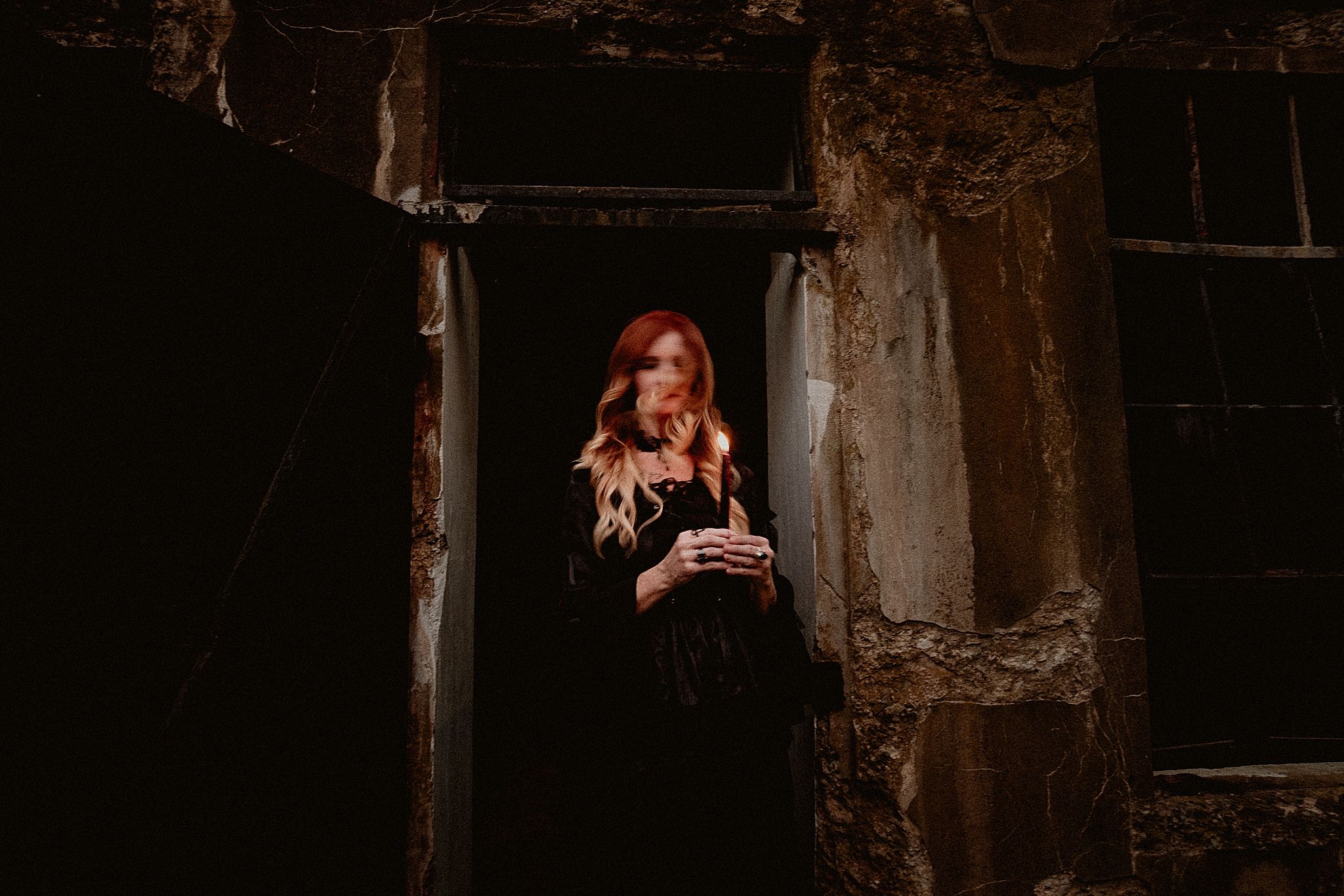 A person in a dark hallway stands illuminated by natural light streaming through windows.