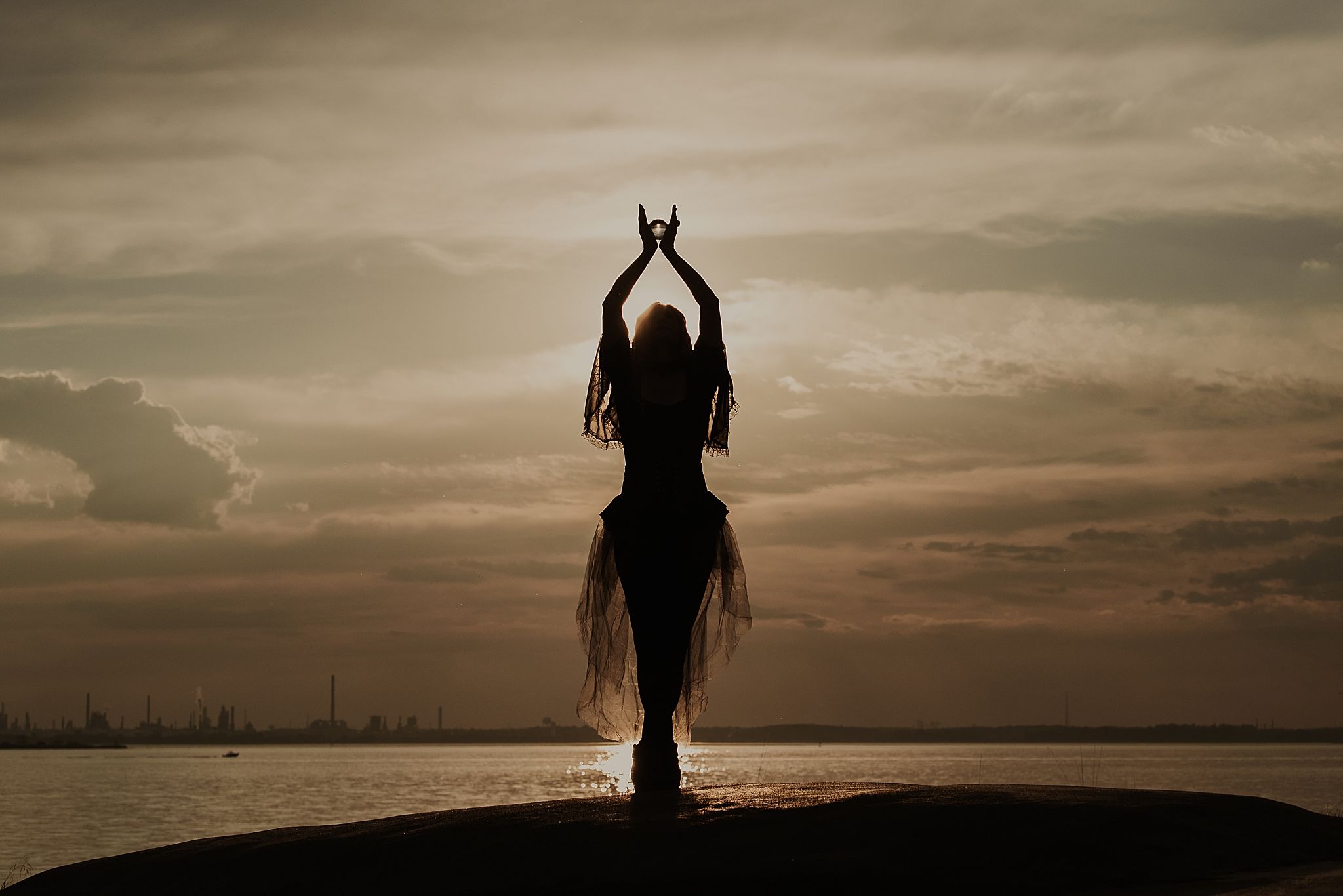 Silhouettes of figures standing on a beach at sunset creating a dramatic moody atmosphere against a cloudy sky.