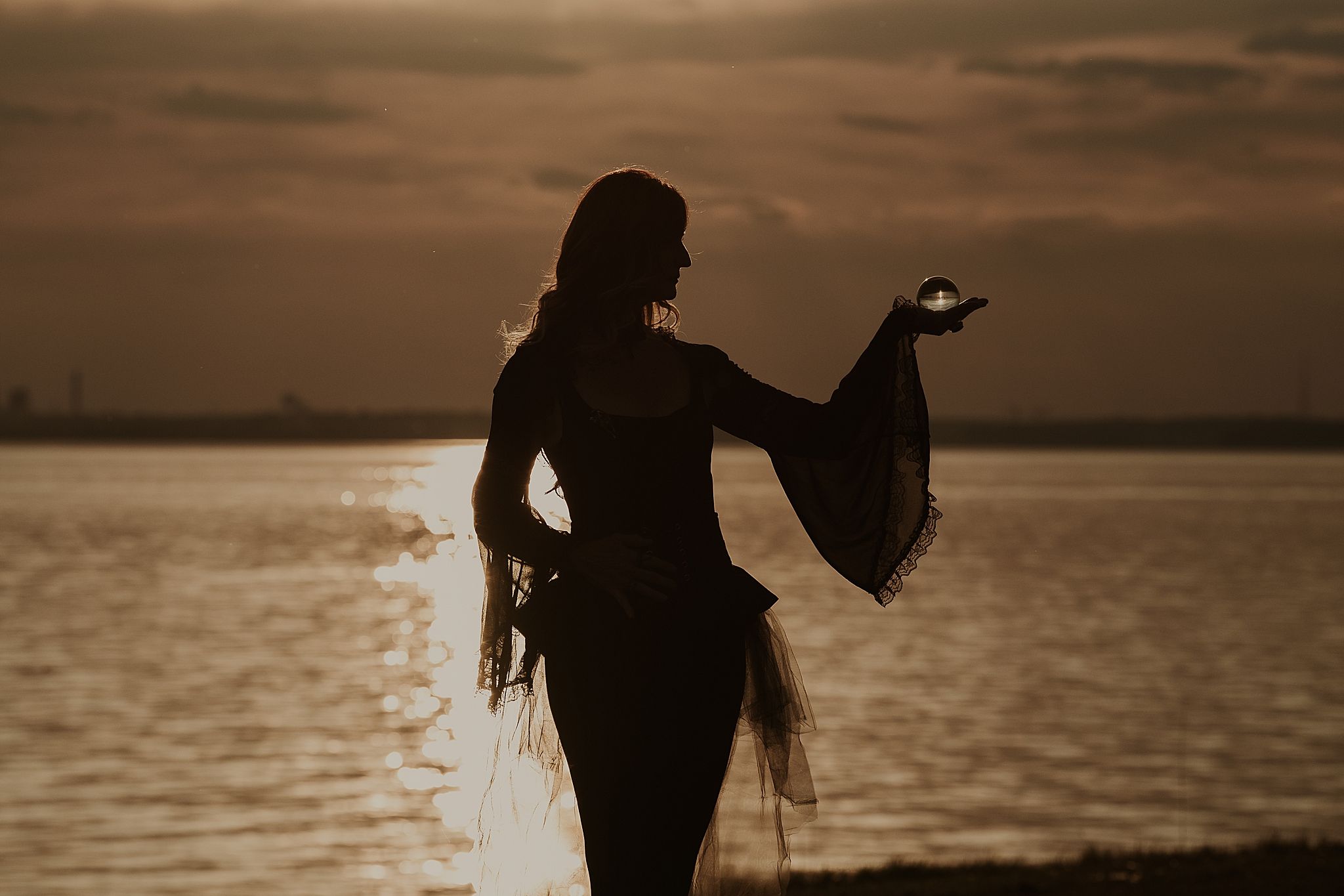 Silhouetted figures dance and pose along a beach shoreline at sunset creating romantic and joyful shadows.
