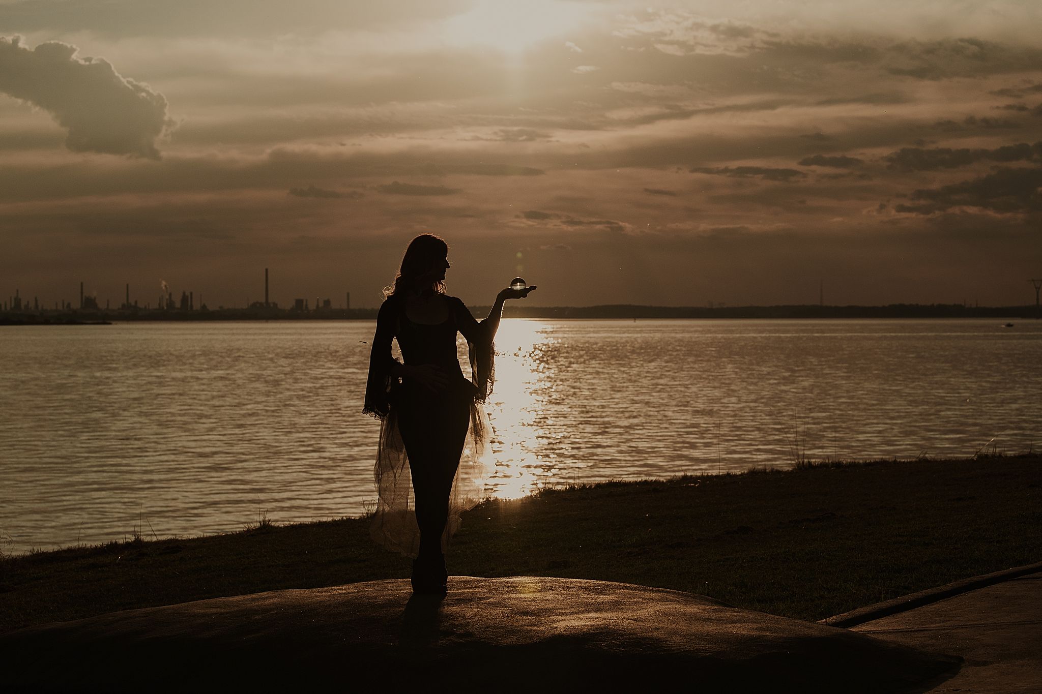 Silhouetted figure walks along a beach pier at sunset with dramatic orange sky and calm waters.