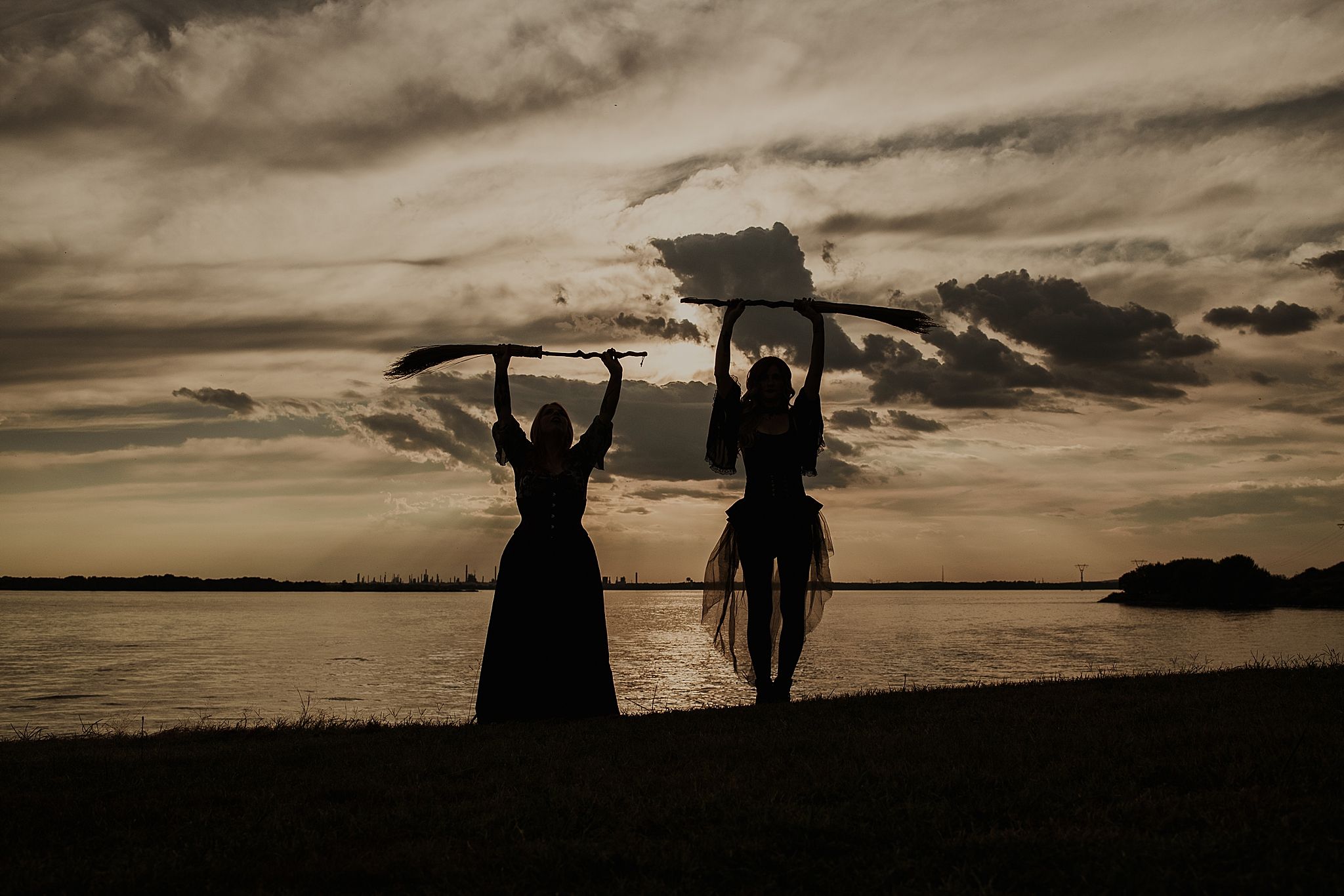 Silhouettes of people enjoying sunset at beach with dramatic cloudy sky and ocean waves in background.