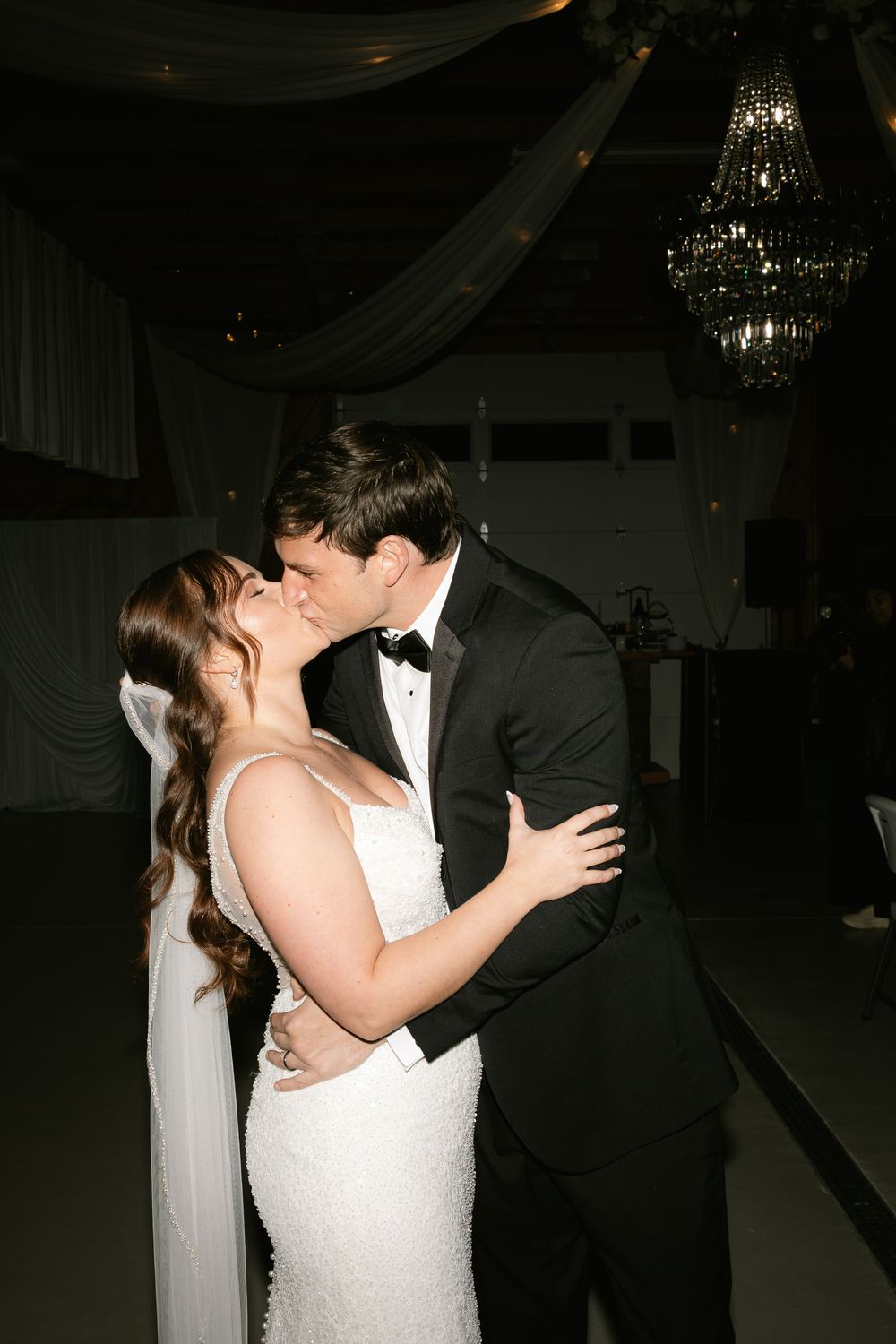Romantic first dance moment under crystal chandeliers at wedding reception.