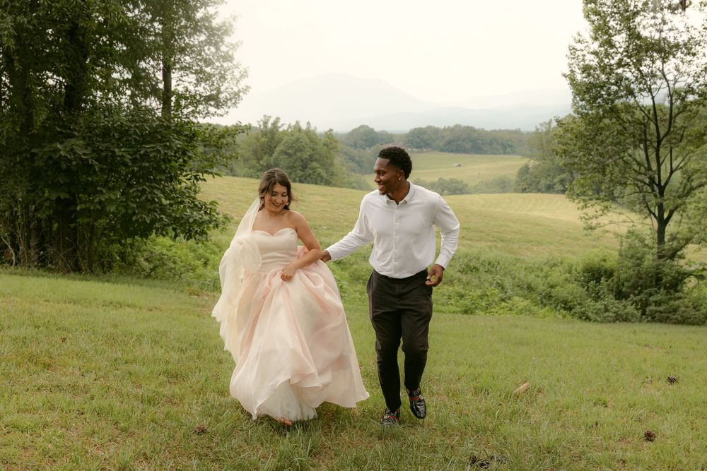 A wedding couple walks together through a scenic meadow while holding hands at Sierra Vista Wedding Venue
