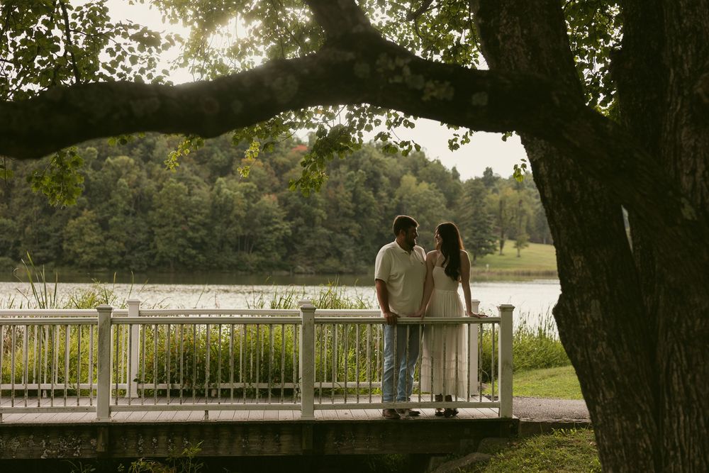 A scenic lakeside gazebo view framed by tree branches at dusk.