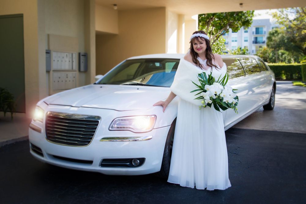 A white limousine parked under a covered entrance with white floral decorations.