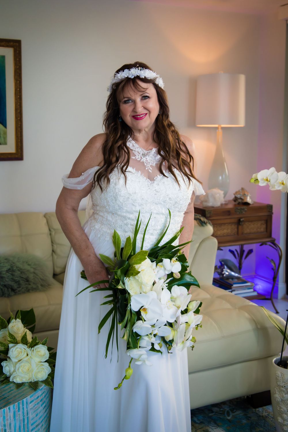 Multiple shots of a white wedding dress with floral details and a white lily bouquet in an indoor setting.