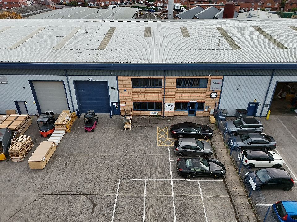 Aerial view of commercial warehouse buildings with white roofs and parking lots in an industrial area.