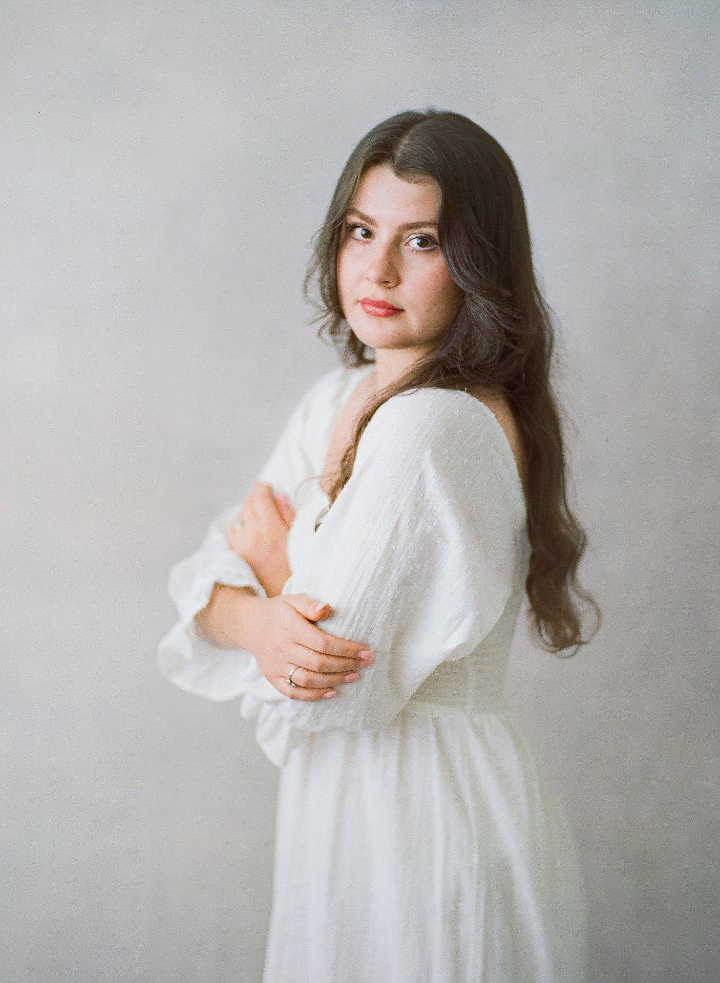 Artistic portrait in white flowing dress against neutral background.